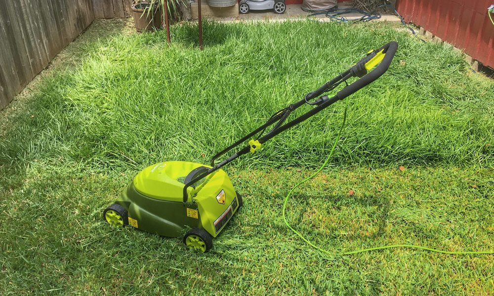 small electric lawn mower on half cut lawn