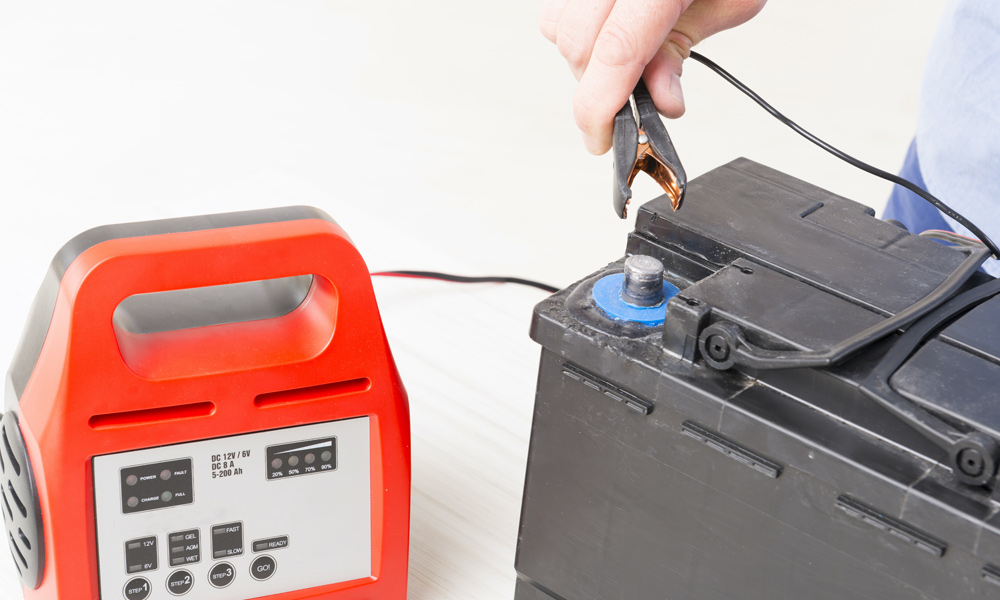 a car battery charger connecting to a car battery 