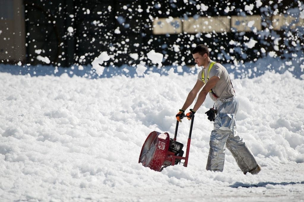 A workman using snow blower