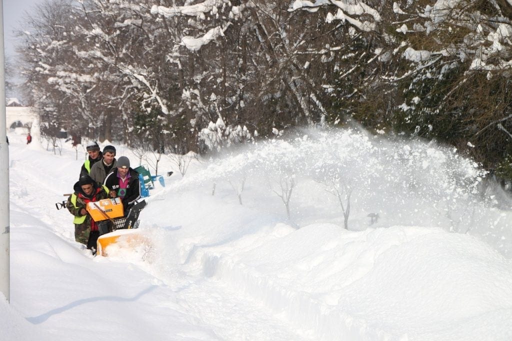 Four people using a Snow Blower