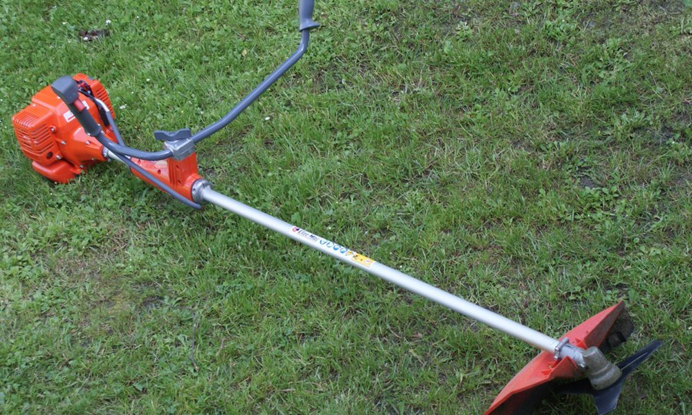 Orange string trimmer laying on grass