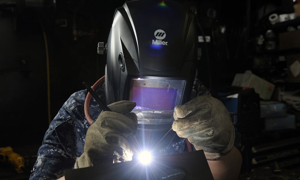 someone using a welder with bright light shining off helmet