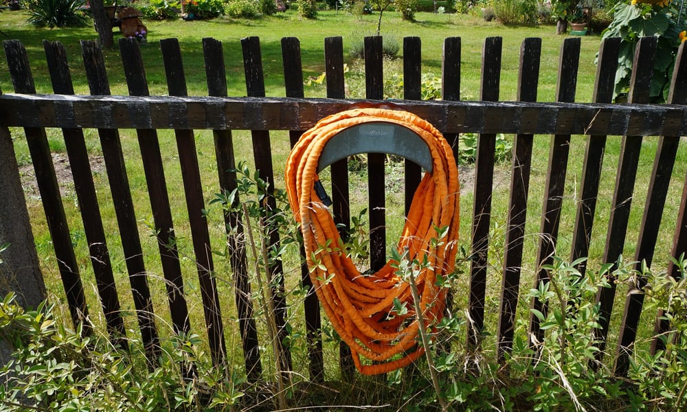 Expandable garden hose hanging on a fence