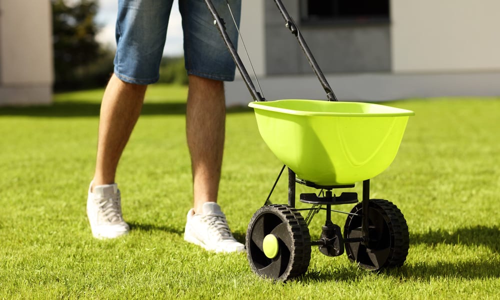 pushing a lawn spreader cart over grass