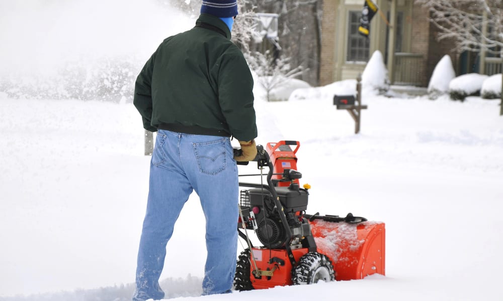 A man clearing a pathway with a snow blower