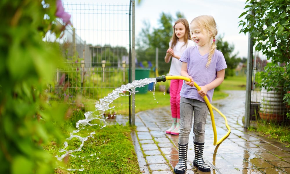 little girl holding a garden hose
