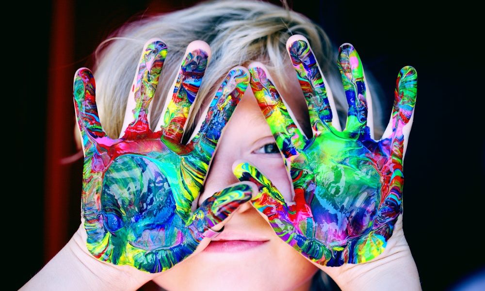 kids hands covered in multi color paints
