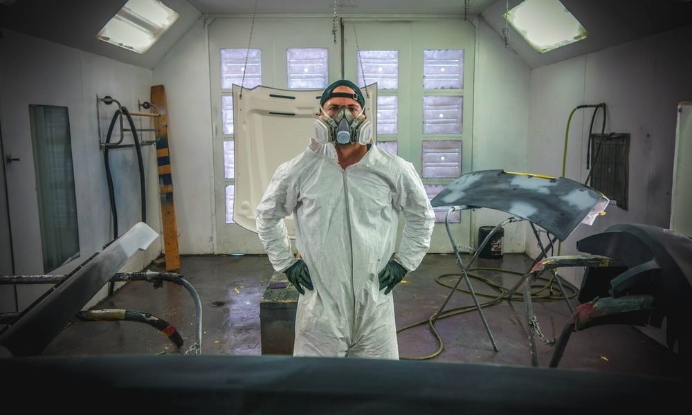 a man in a paint shop room wearing white jump suit