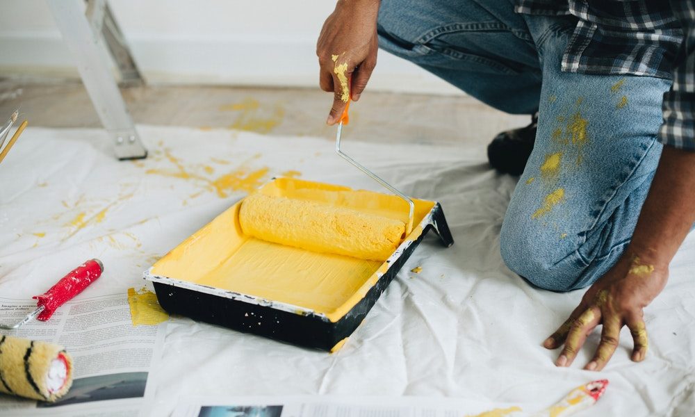 yellow paint roller in a paint tray