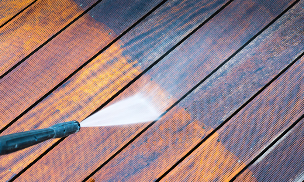 Pressure washer nozzle cleaning a wood decking