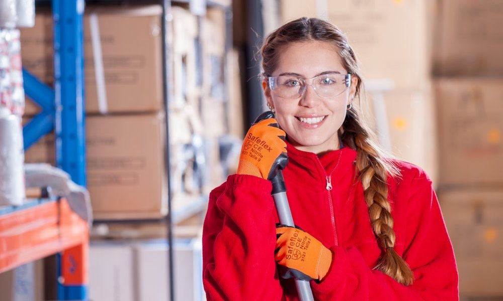 women wearing safety glasses and gloves holding a broom
