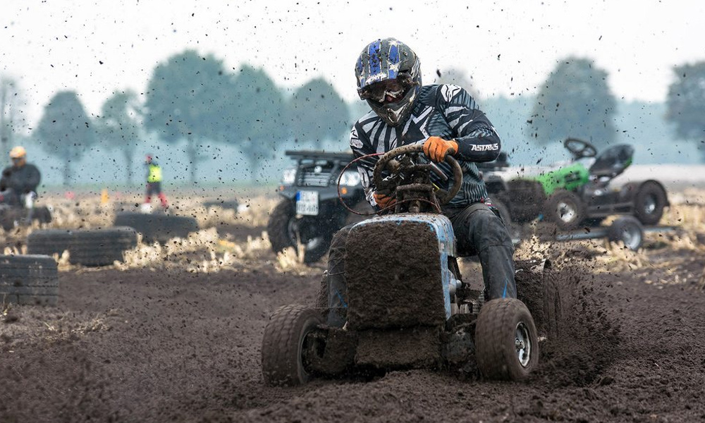 close up of a race lawn mower covered in mud