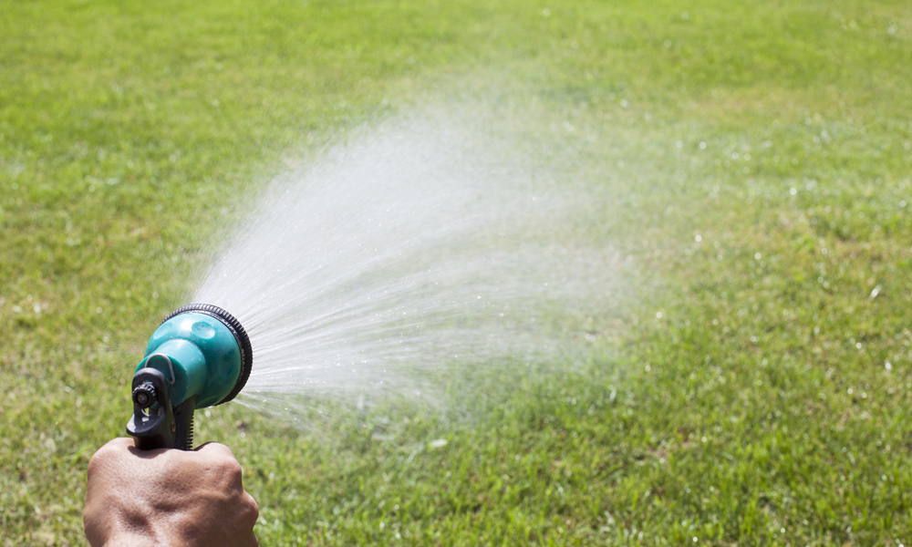 garden hose spray gun watering a lawn