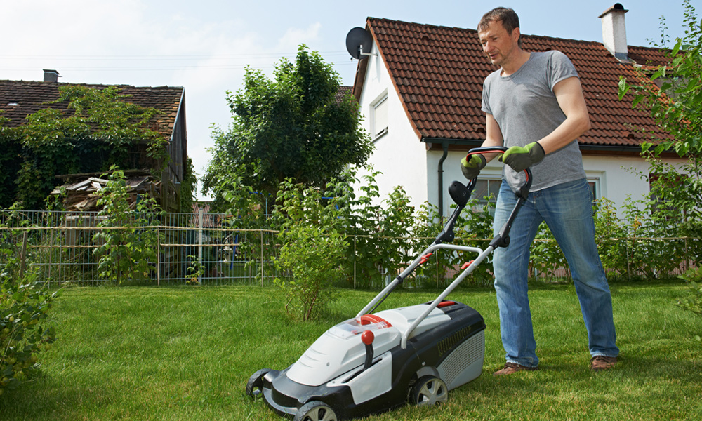 a man pushing a lawnmower over grass