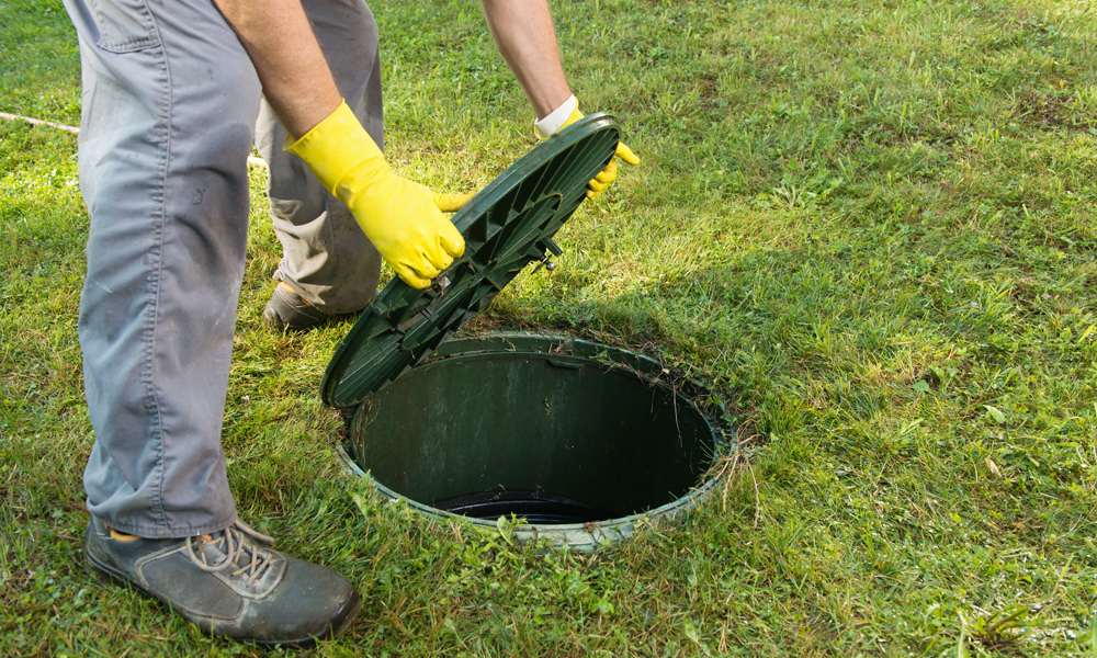 A man opening up a Septic Tank cover