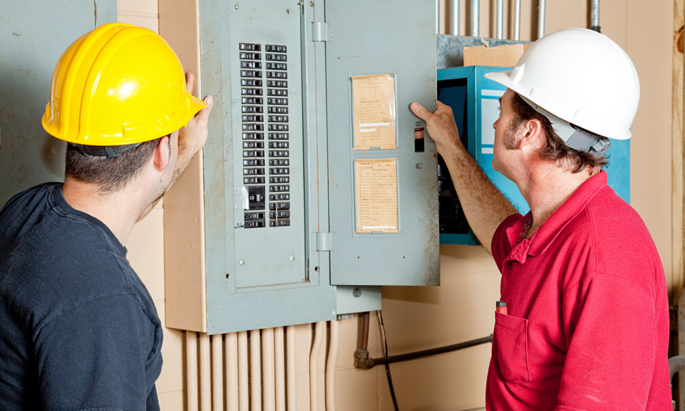 two builders looking at a breaker box