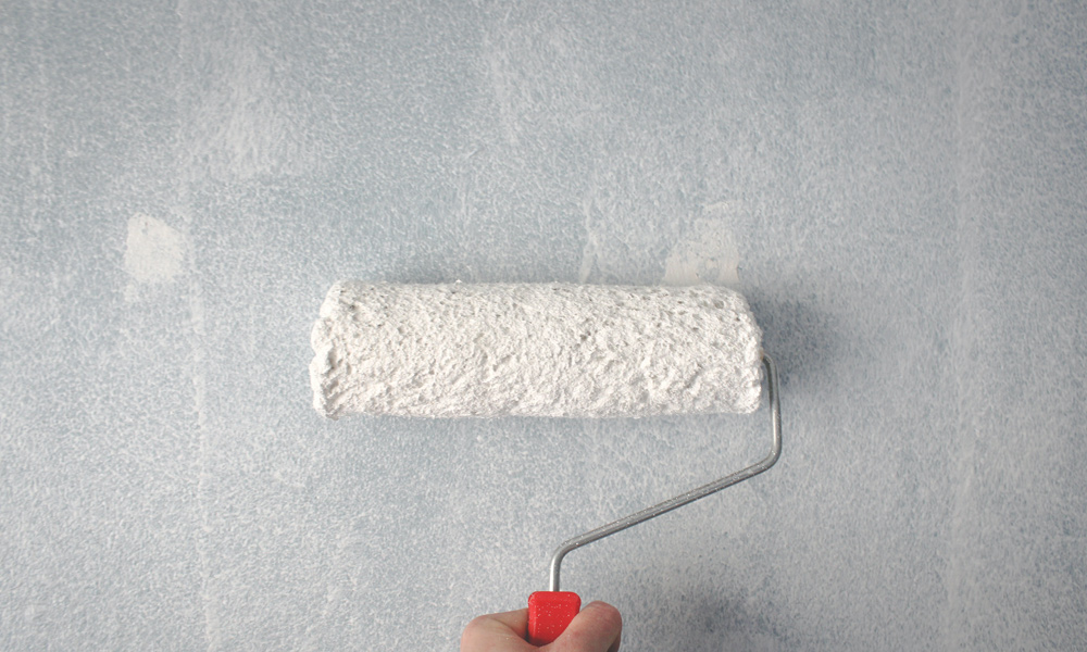 A paint roller on a painted wall