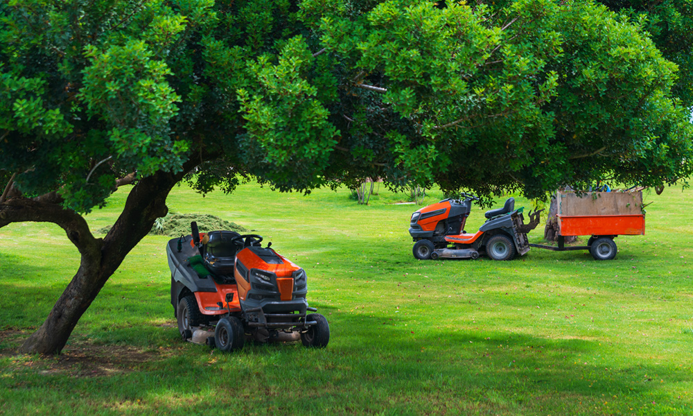 Two riding lawn mowers on grass.