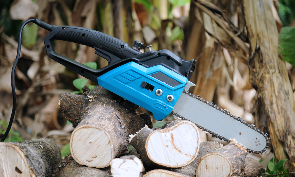 Blue electric chainsaw resting on wood logs