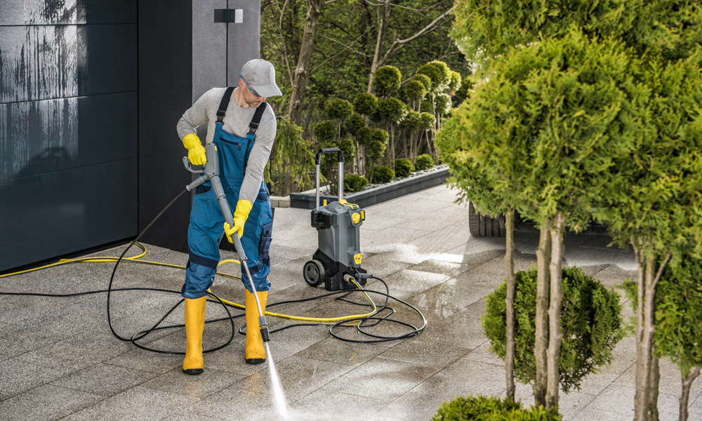 Someone using a pressure washer in safety gear