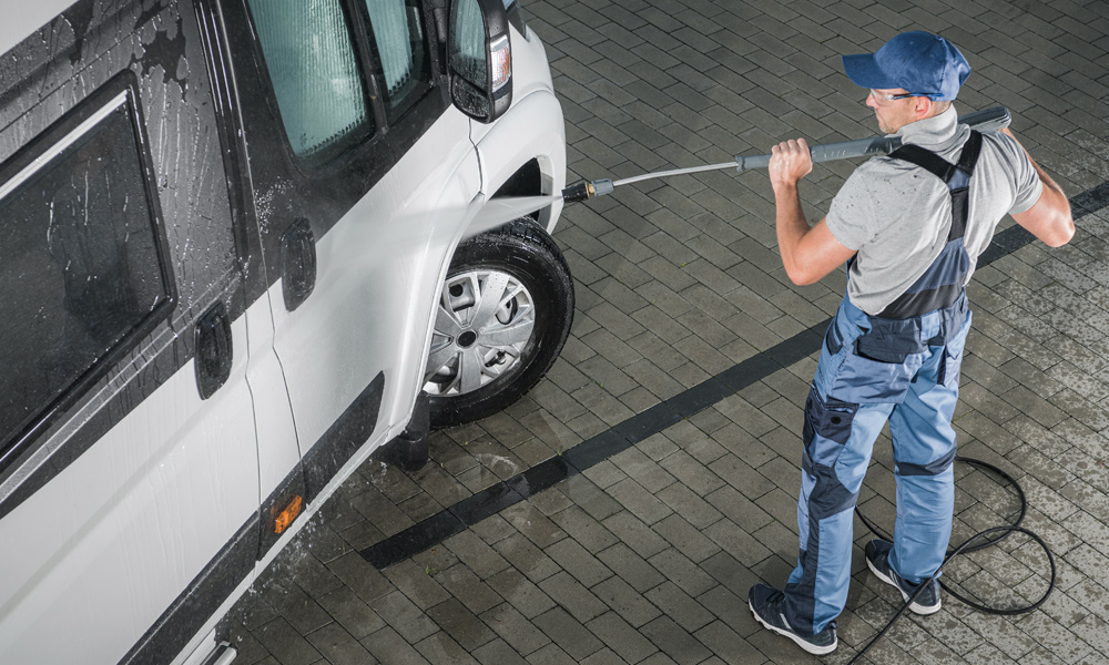 Man washing a van with a pressure washer