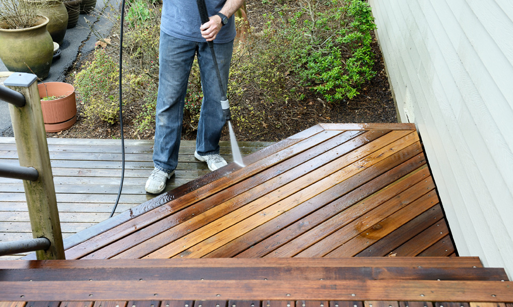 Someone using a pressure washer on decking
